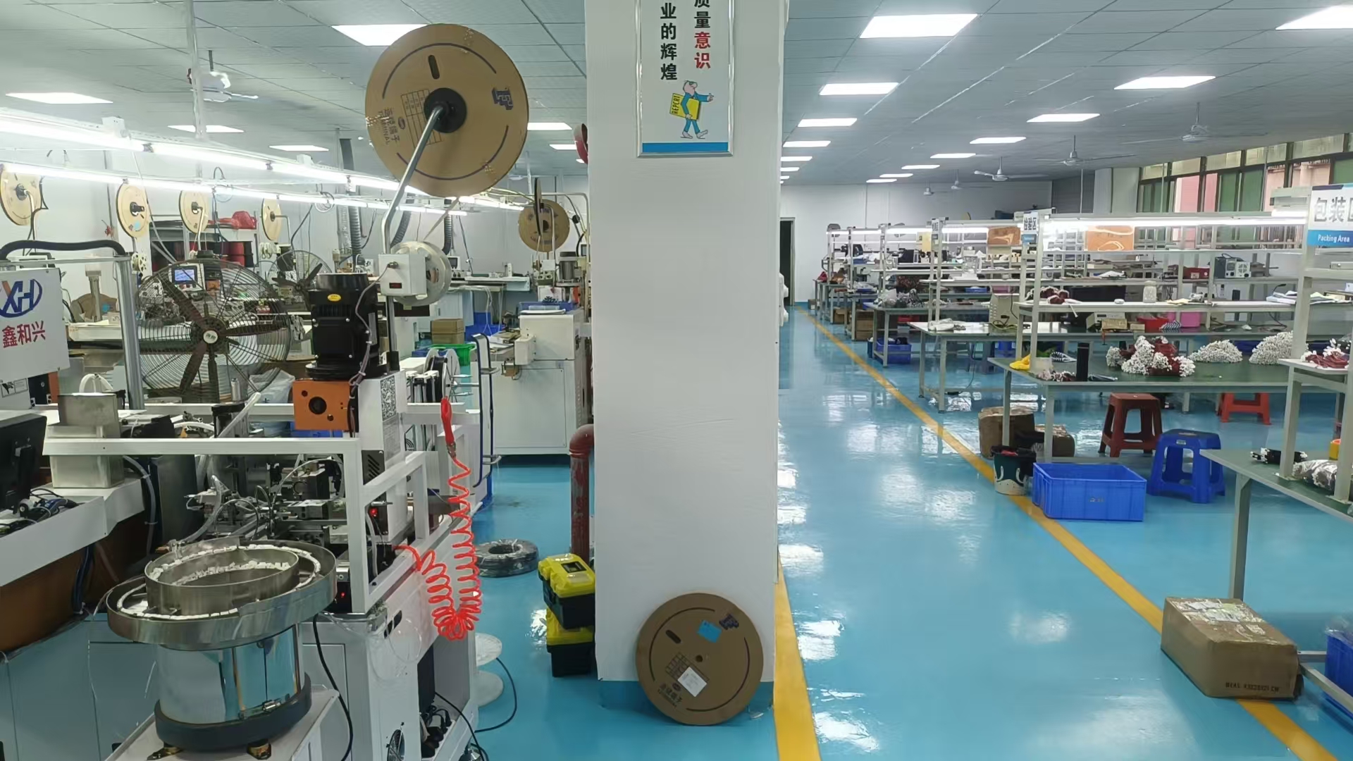 Professional cable manufacturing facility with various wire harness products on workbench, showing precision tools and quality control equipment in clean industrial environment